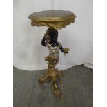 A carved wooden Blackamoor plant stand supporting a shaped circular top on three scroll supports,
