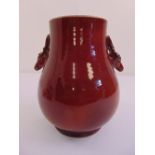 A Chinese ox blood red glazed pear shaped vase with mask side handles on rim foot