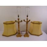A pair of gilded metal and marble table lamps on triform bases with silk shades