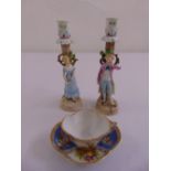 A pair of ceramic figural candlesticks and a Dresden cup and saucer, marks to the base