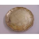 A Victorian silver salver shaped circular with gadrooned border on three stepped hoof feet, London
