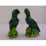 A pair of ceramic figurines of parrots on raised naturalistic bases
