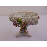 A continental porcelain sweetmeat dish on raised triform base with applied floral clusters