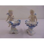 A pair of Sitzendorf salts in the form of putti supporting baskets, marks to the bases