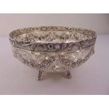 A white metal fruit bowl, circular with scroll pierced sides, chased with floral swags and birds