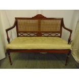 An Edwardian rectangular two seater Sheraton style settle with bergere back and seat on four