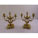 A pair of brass two light candelabra on shaped square bases with scroll supports