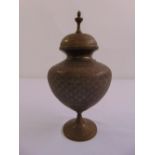 An Indian brass baluster vase and cover on raised circular base chased with scrolls, flowers and