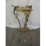 A brass plant stand on three outswept legs decorated with scrolls, leaves and flowers