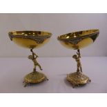 A pair of brass bowls supported by putti on raised circular bases