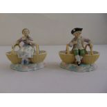 A pair of Augustus Rex porcelain salts in the form of a boy and a girl supporting baskets on