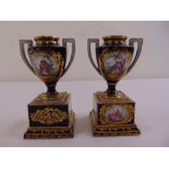 A pair of continental ceramic vases with pierced side handles on square plinths decorated with