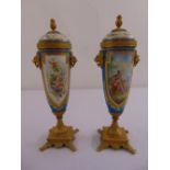 A pair of French style tapering cylindrical porcelain garnitures with gilded metal mounts