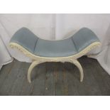 A curved white painted upholstered boudoir stool on sabre legs