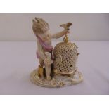 A Meissen figurine of a putti with a birdcage on raised oval base, marks to the base, A/F