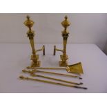 A pair of brass fire dogs and three piece brass companion set
