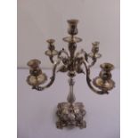 A continental white metal four branch candelabrum, the leaf and shell chased baluster stem on raised