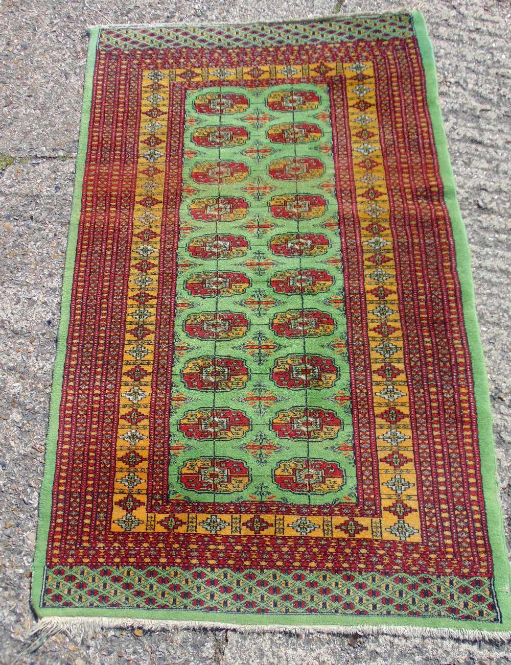 Persian wool carpet green ground with repeating motif design, predominately red and green border