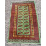Persian wool carpet green ground with repeating motif design, predominately red and green border