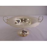 A silver fruit stand circular cut edge with two scrolling side handles on raised circular base,