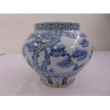 A Chinese blue and white squat vase decorated with trees and flowers