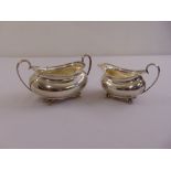 A silver strawberry set comprising sugar bowl and cream jug, rounded rectangular with gadrooned