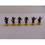 Six cast metal figurine place card holders on raised circular bases