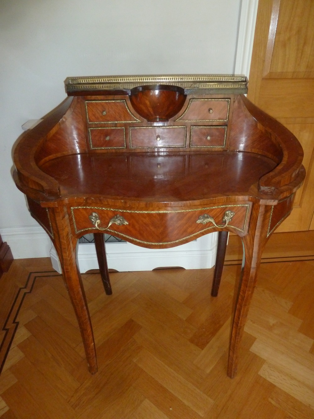 A kingswood shaped oval inlaid desk with gallery and six drawers on cabriole legs