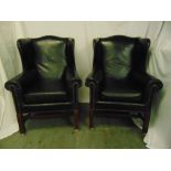 A pair of black leather armchairs on fluted rectangular mahogany legs