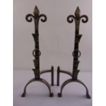 A pair of brushed metal fire dogs with Fleur de Lys terminals on arched supports