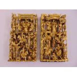 A pair of rectangular oriental gilded wooden plaques carved with figures, horses and pavilions