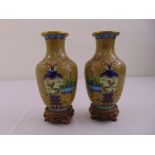 A pair of cloisonné baluster vases decorated with flowers and leaves on hardwood stands