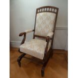 An Edwardian mahogany upholstered rocking chair on four turned supports