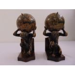 A pair of moulded bookends of Charles Atlas holding globes, mounted on wooden plinths