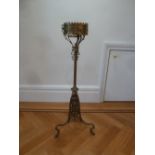 A brass Gothic style plant stand on three scroll supports