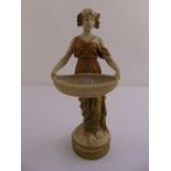 Royal Dux figurine of a lady in classical dress holding a basket, on raised circular plinth, marks