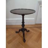 A mahogany side table with pie crust circular border with baluster stem on outswept legs