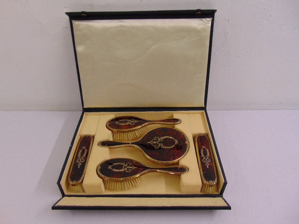 A cased silver gilt and tortoiseshell five piece dressing table set to include two hair brushes, two