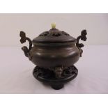 A Chinese bronze incense burner with hardwood pull off cover inset with jade finial on a pierced