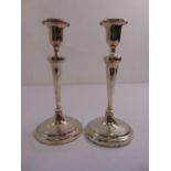 A pair of George III filled silver table candlesticks, tapering cylindrical, engraved with floral