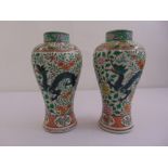 A pair of oriental baluster vases decorated with dragons, flowers and leaves