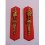 Two cast ormolu figurines in 17th century attire on leaf chased prints mounted on red fabric panels