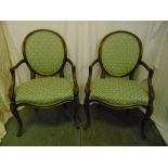 A pair of French upholstered mahogany armchairs, oval backs, scroll arms and legs