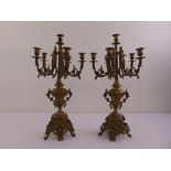 A pair of gilded metal five branch candelabra, the urn shaped stems supporting scrolling arms on