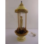 A decorative oil lamp in the form of a classical maiden framed by a domed cover and circular base