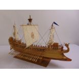 A wooden ships model of a Bireme with linen sails on raised rectangular plinth