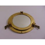 A brass and glass ships porthole of customary form converted to a wall mirror