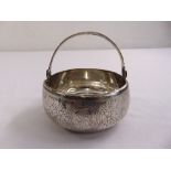 A Russian silver sugar bowl of circular form with swing handle, the sides engraved with flowers