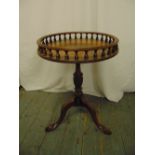 A circular mahogany side table with raised pierced gallery on three scroll legs