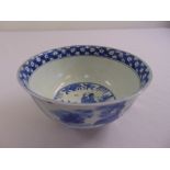 A Chinese blue and white bowl with images of figures in a landscape, marks to the base